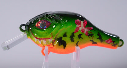 The Sinister Squarebill in Toxic Tiger is a bold 0.7 oz crankbait built to crash through cover and trigger reaction bites. Designed to dive 3–5 feet, this lure excels in shallow water where big bass ambush prey. Its Toxic Fire Tiger color pattern combines fluorescent greens, fiery oranges, and sharp contrast lines that stand out in stained or low-light conditions — perfect for getting noticed when visibility is tough.

The squarebill design gives it a hard-hunting, deflective action that bounces off wood.