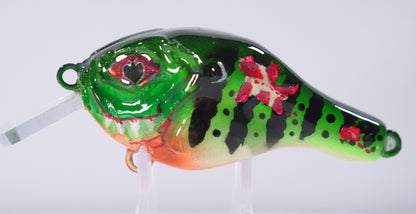The Sinister Squarebill in Toxic Tiger is a bold 0.7 oz crankbait built to crash through cover and trigger reaction bites. Designed to dive 3–5 feet, this lure excels in shallow water where big bass ambush prey. Its Toxic Fire Tiger color pattern combines fluorescent greens, fiery oranges, and sharp contrast lines that stand out in stained or low-light conditions — perfect for getting noticed when visibility is tough.

The squarebill design gives it a hard-hunting, deflective action that bounces off wood.